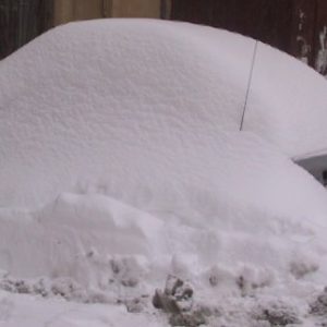 La neve cade improvvisa dal tetto della scuola a Tolmezzo e seppellisce le auto