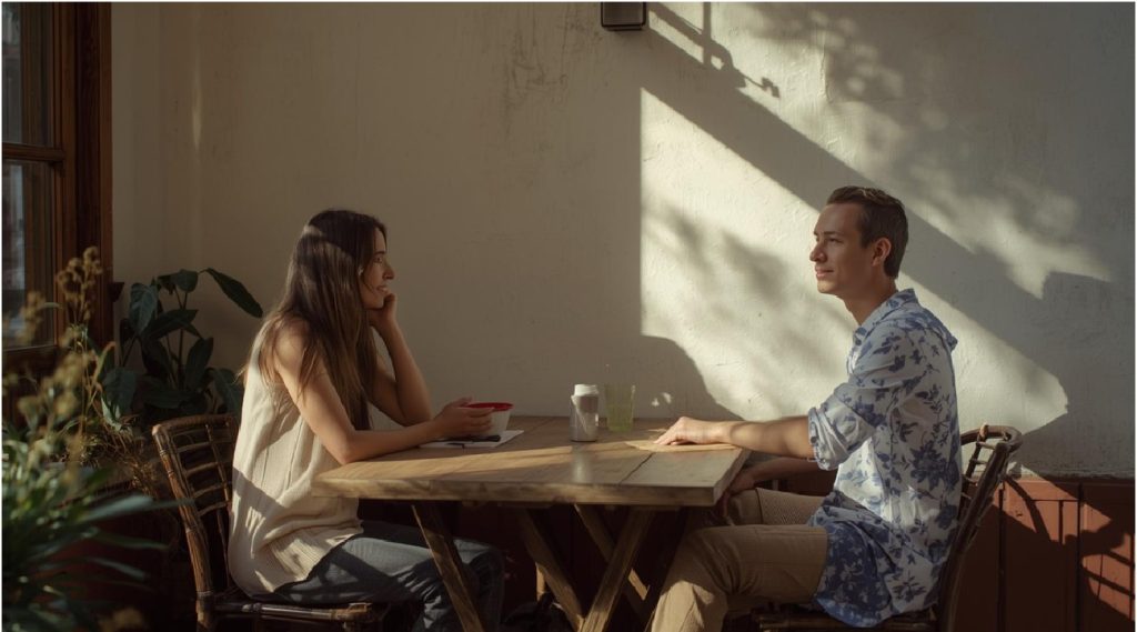 Due persone sedute a un tavolino che conversano con calma davanti a un caffè.